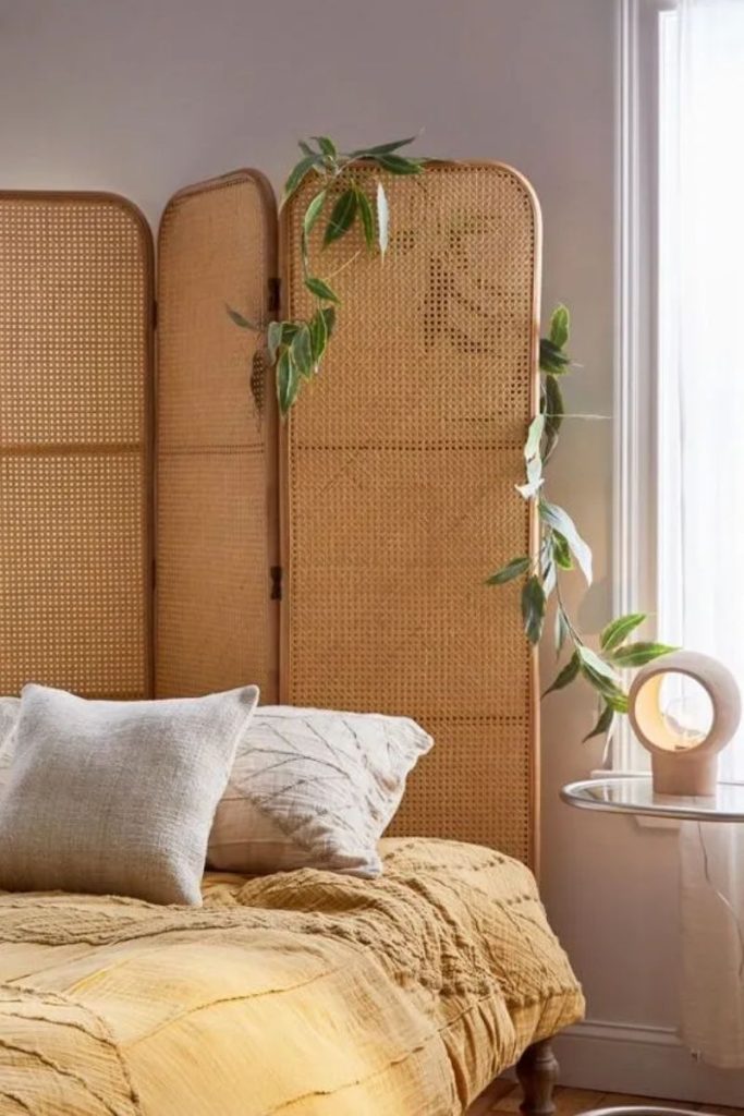 Rattan room divider as a headboard with a faux vine plant