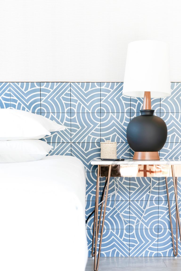 Patterned blue and white background behind bed and bedside table as a no headboard idea.